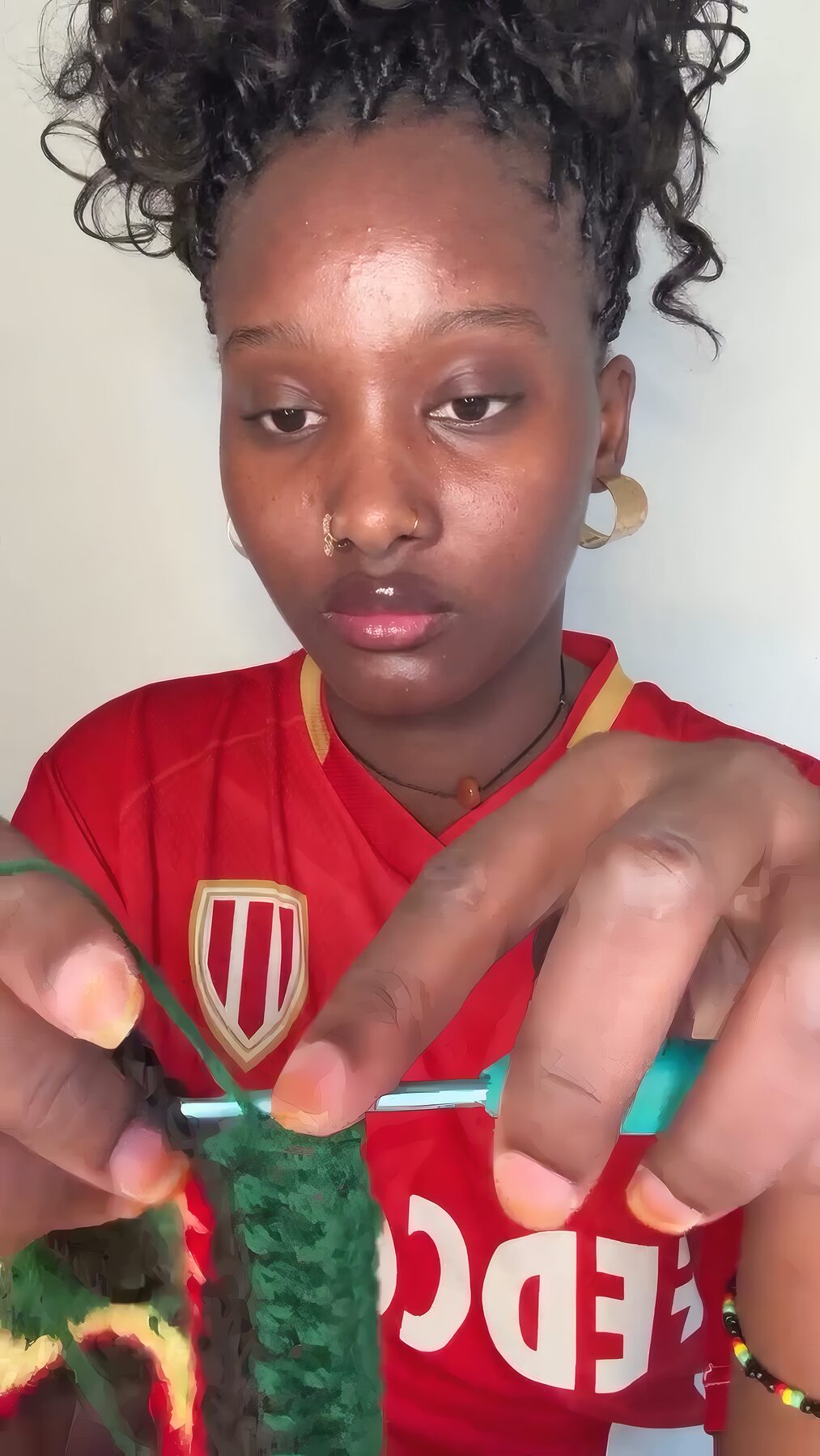 Gros plan des mains et du crochet turquoise formant une bande aux couleurs rasta