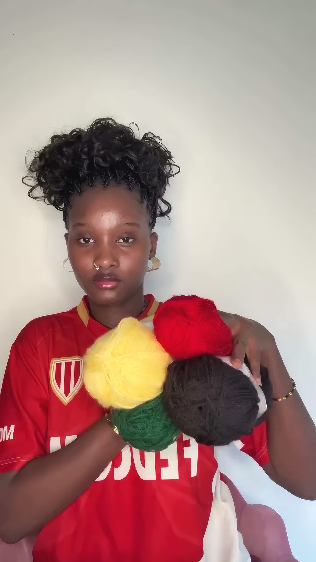 Rama tient des pelotes de fil colorées dans son atelier