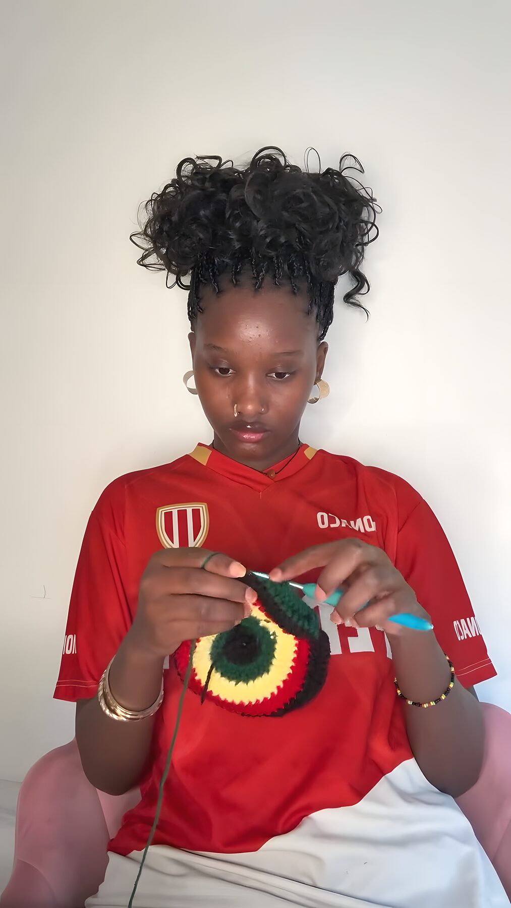 Rama crochète un bonnet à la main dans son atelier, crochet et fil en main