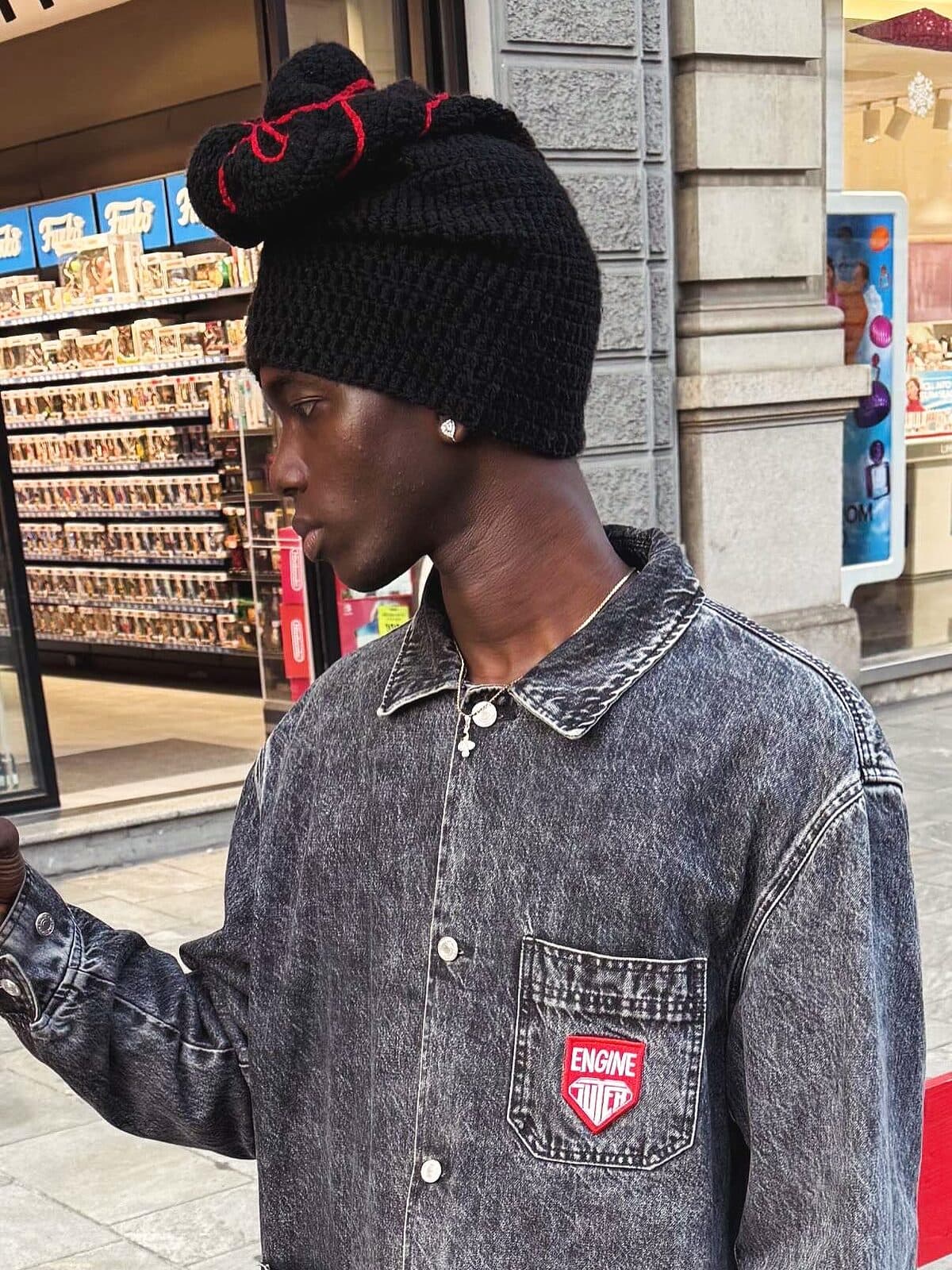 @ibrahtall porte le Bonnet Invention noir devant une vitrine, lumière du jour
