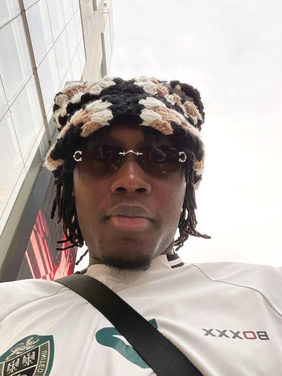 @sekou_doumbouya_ porte un bonnet granny noir et blanc, en extérieur plein jour