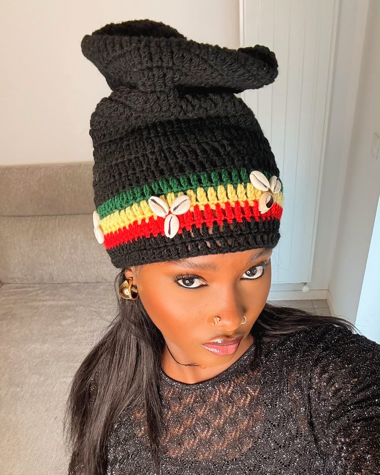 Bonnet Champion noir à bande rasta et cauris, porté en intérieur, lumière du jour