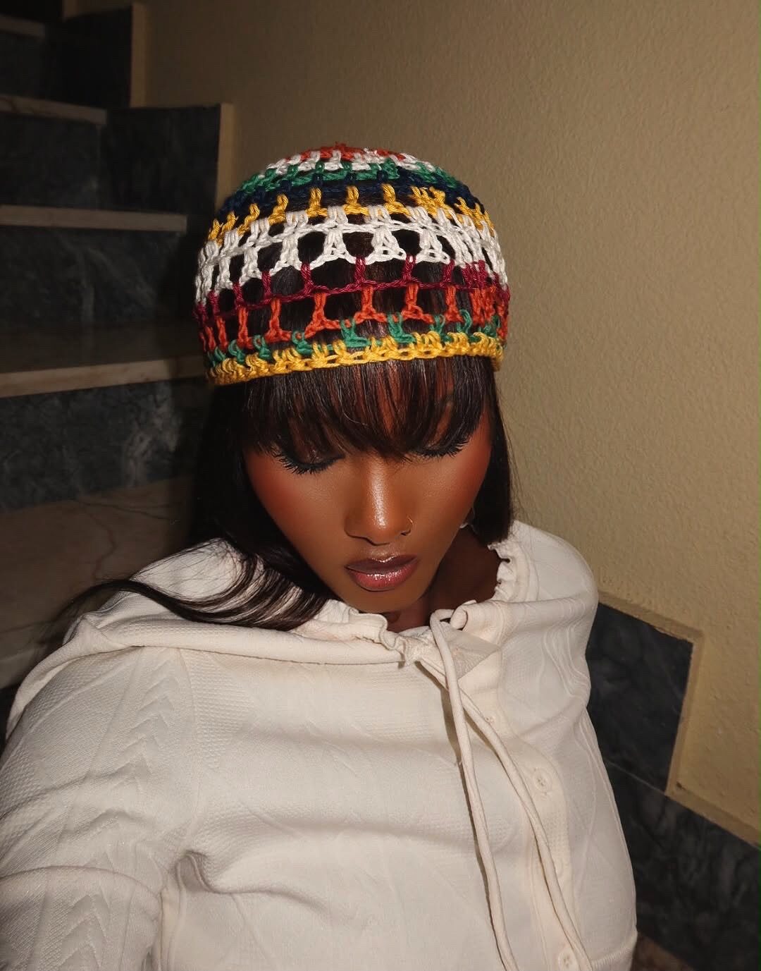 Bonnet crocheté ajouré aux tons verts, jaunes et rouges, porté avec un sweat à capuche blanc