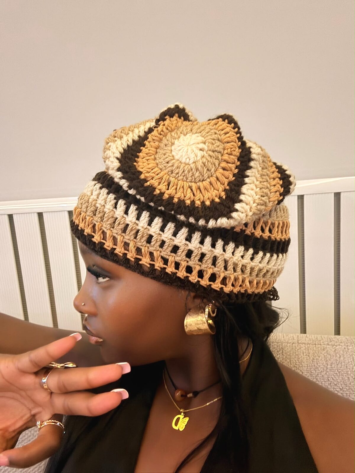 Bonnet crocheté à motif concentrique brun et crème, porté de profil en pleine lumière du jour